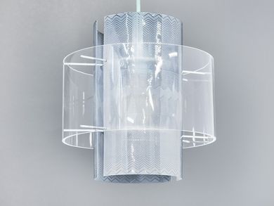 The lamp is hung on a white cord. The light bulb is encased with transparent, rounded plexiglass panes that are engraved with decorative zigzag lines. 