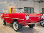 Das feuerrote Amphicar hat deutlich mehr Bodenfreiheit als ein normales Auto. Es sieht aus wie ein Cabrio und ähnelt im Design anderen Wagen der frühen 1960er Jahre: runde Glubschaugen-Scheinwerfer, angedeutete Flossen am Heck.