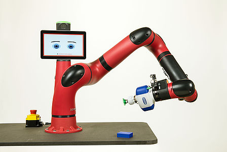 Man sieht einen rot-schwarzen Roboterarm, der an seinem Greifarm eine kleine Saugvorrichtung hat. Auf dem Bedienungsdisplay erscheinen zwei Augen.