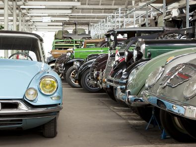 Blick in das Automobil-Depot des Deutschen Technikmuseums. Rechts stehen zahlreiche Autos dicht an dicht auf dem Boden und in einem großen Regal darüber. Links steht ein hellblauer Citroen DS 19.