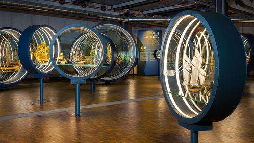 In der Ausstellung stehen lupenförmige Rundvitrinen. Darin sind Schiffsmodelle zu sehen.