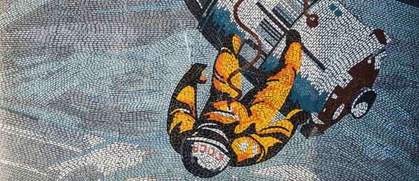 The mosaic depicts a cosmonaut in a yellow suit floating in space above the Earth. He is connected to a space capsule by a hose.