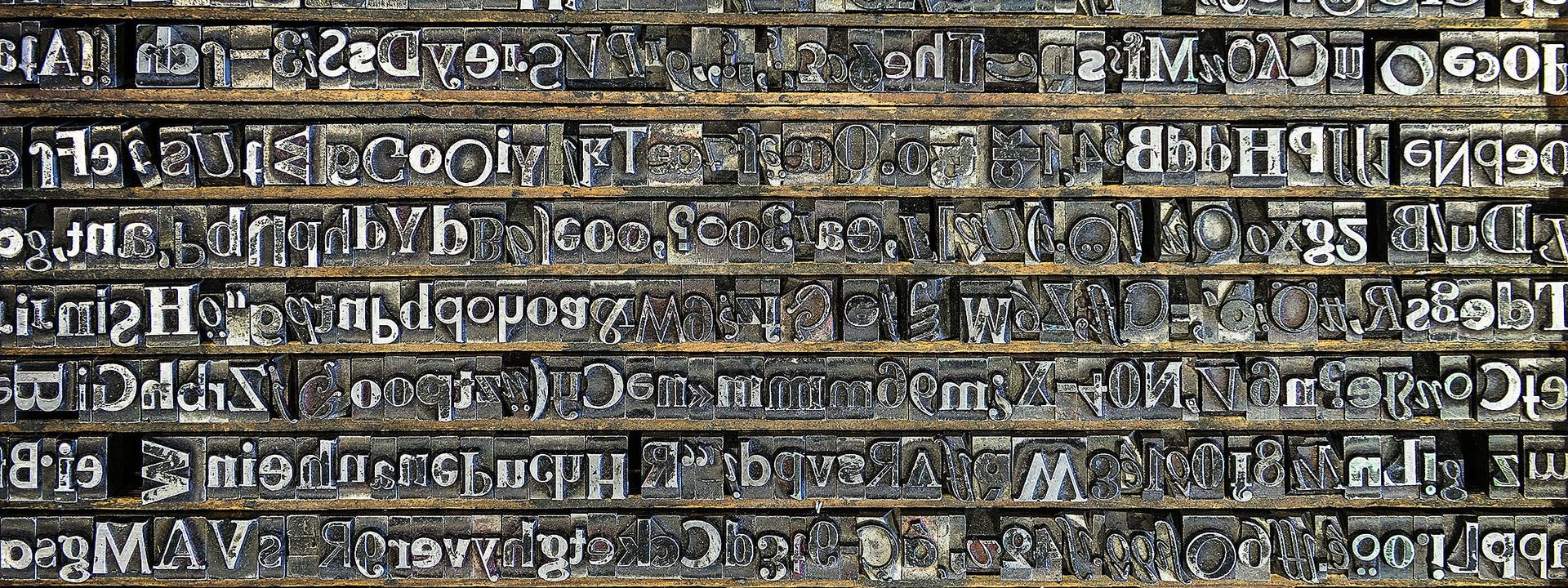 Many different types – raised, inverse letters made of lead – are arranged in a type case.