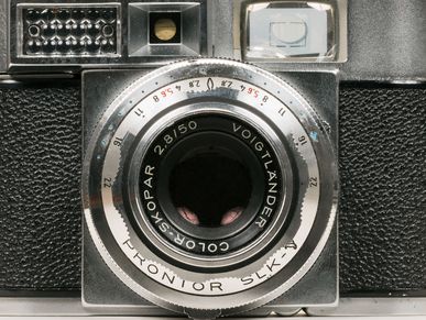 Fotokamera mit schwarzem Gehäuse und silbernem Objektiv.