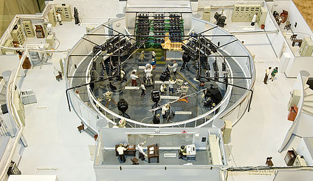 A circular television studio divided into two levels. The studio, including a stage, is below. The control room is above.