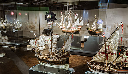 Ein mit Vitrinen gesäumter Gang, darin verschiedene Modelle von Segelschiffen.