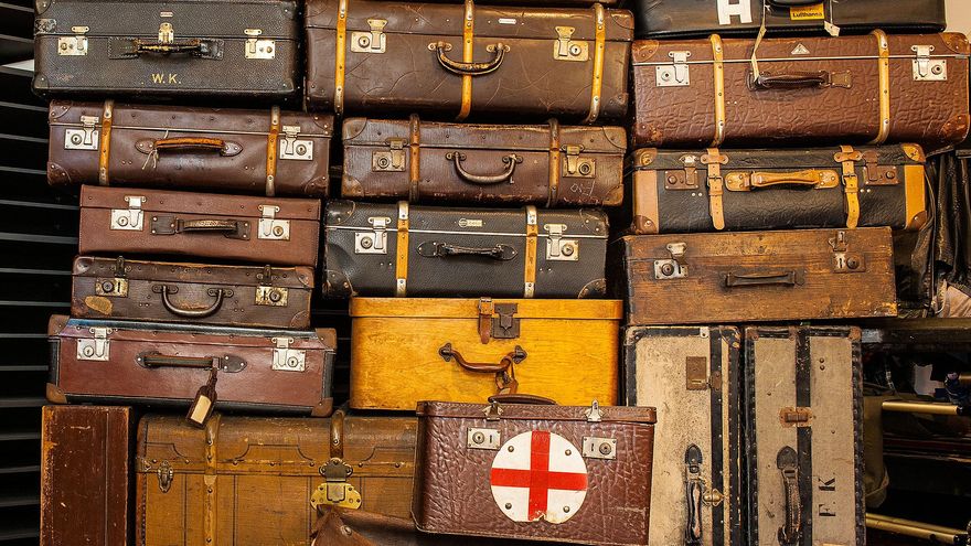 Ein hoher Stapel aus verschiedenen, historischen Koffern in Braun- und Schwarztönen. Die meisten Koffer sind aus Leder, einige aus Holz oder Hartpappe. 
