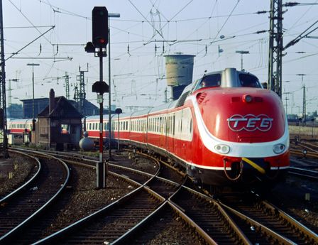 Ein rot-weißer Zug mit rundem Kopf fährt auf einer Schiene ins Bild. Es handelt sich um den 1957 gebauten TEE.