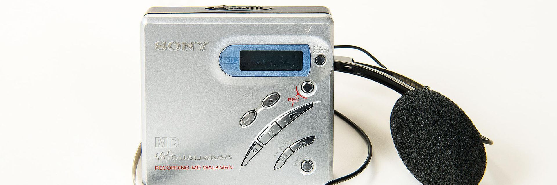 This MZ-R500 MiniDisc Recorder has the shape of a small square box with asymmetrically arranged function keys and a silver colored aluminum surface.