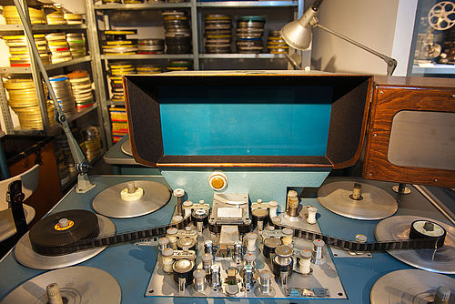 Film editing table with a monitor and various “plates” with rolls of film mounted on them.