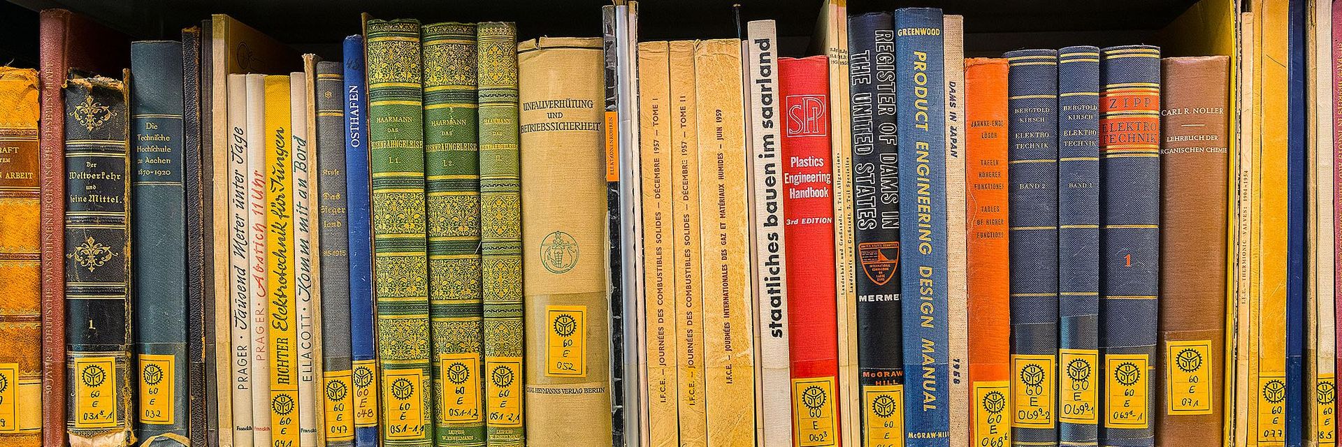 Blick in ein Regal, in dem bunte Buchrücken zu sehen sind, die mit gelben Signaturen ausgestattet sind.