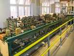 Die Maschine ähnelt einer mehrere Meter langen Werkbank. Auf ihr sitzt ein System von mehr als 15 Walzen verschiedener Größen, durch die die Papierbahn läuft.