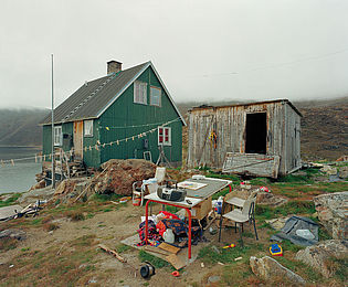 Ein grünes Haus in Grönland, daneben ein einfacher Schuppen.