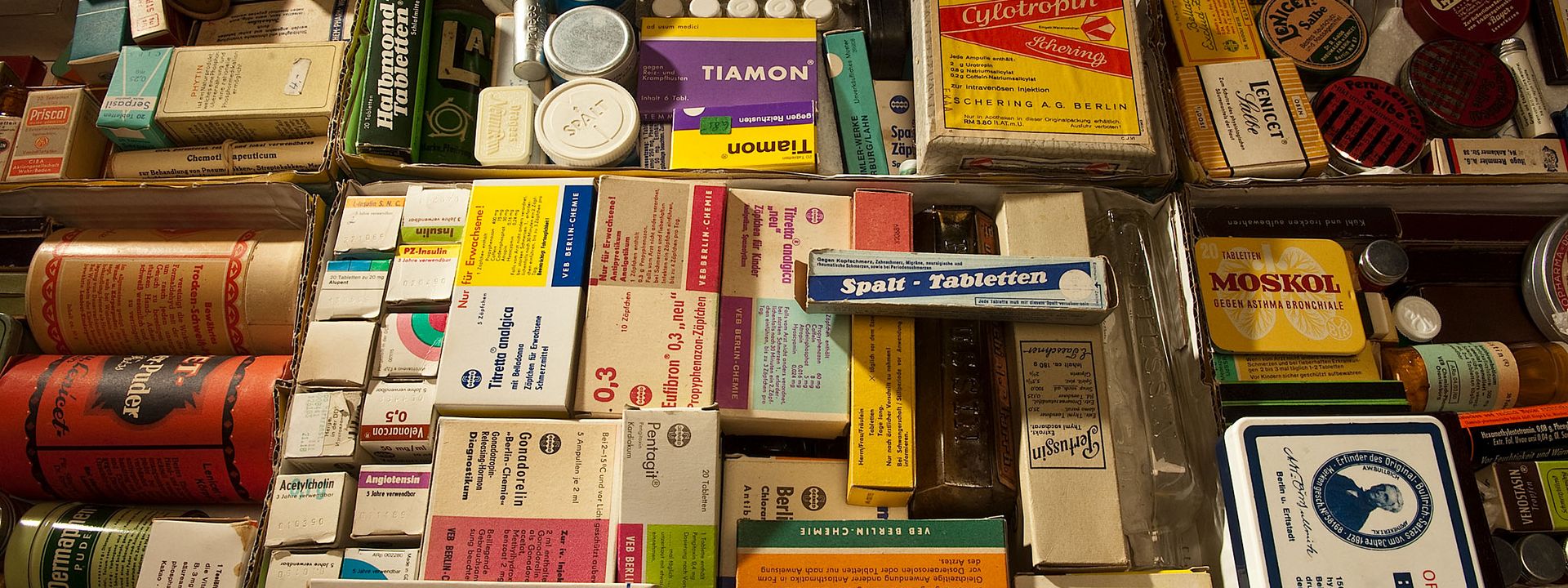 Historische Medikamentenschachteln, Röllchen und Dosen liegen dicht an dicht. Es sind bekannte Marken des alltäglichen Gebrauchs von Kopfschmerz- und Magenmitteln dabei.