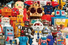 Viele bunte Spielzeugroboter in unterschiedlichen Größen und Formen stehen bildfüllend nebeneinander.