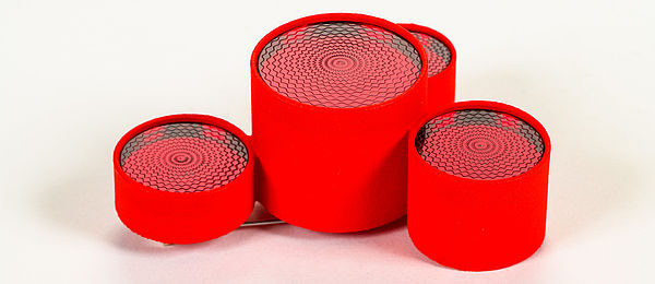Rote Brosche aus vier unterschiedlich hohen roten Acrylglas-Zylindern. Verziert mit eingravierten Rosetten.