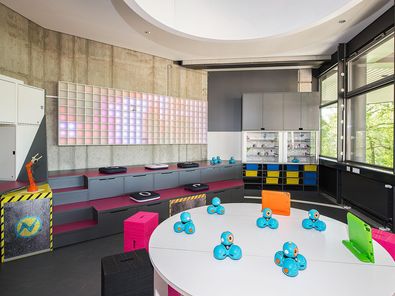 Blick in den Innenraum des kids.digilab.berlin mit bunten Möbeln, Tischen mit Robotikspielzeug und farbenfroher Wandgestaltung.