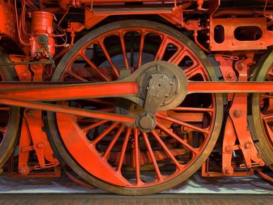 Nahaufnahme von großen, rot gestrichenen Rädern einer historischen Lokomotive. 