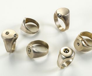 Six silver signet rings with small steel balls pressed into the surface.