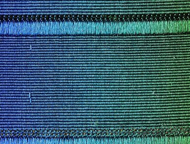Close-up of a woven strap whose color fades from violet to blue to green.