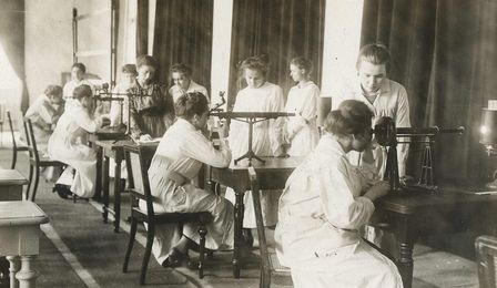 Das Schwarz-Weiss-Foto zeigt mehrere weibliche Auszubildende in Laborkitteln. Einige bedienen einen Polarimeter.