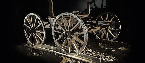 Der Drehschemelwagen besitzt vier Räder und steht passgenau auf den Schienen vor schwarzem Hintergrund.