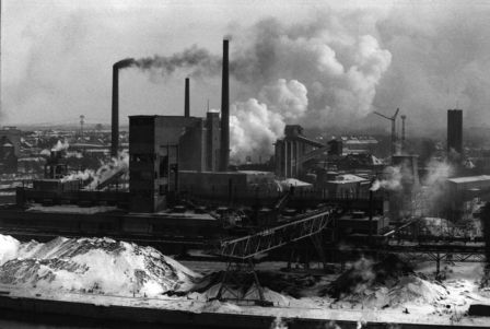 Auf dem Foto ist ein Kraftwerk zu sehen, aus dessen Schronsteinen dichter Rauch aufsteigt.