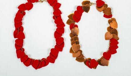 Two copper chains made of many red hearts. Some of the red velvety film has been removed from one of them.