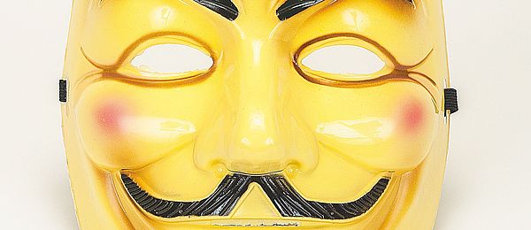 Eine gelbe Guy-Fawkes-Maske mit geschwungenen Augenbrauen, Schurrbart, Unterlippenbart und gerröteten Wangen vor hellem Hintergrund. 