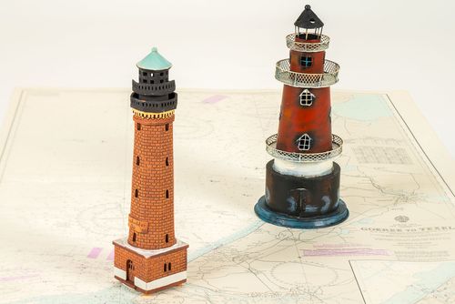 Models of a brick lighthouse and a red and white imaginary lighthouse are standing on a sea chart.