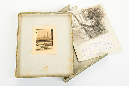 Aufgeklappte Schachtel, darin rechts eine Zeichnung mit einer Widmung. Links ist die Deckelinnenseite zu sehen, auf der Heinrich Hirschbergs Exlibris klebt. Es zeigt im Vordergrund ein aufgeschlagenes Buch auf einem Tisch, im Hintergrund ist durch einen Fensterrahmen eine Fabrik zu erkennen.
