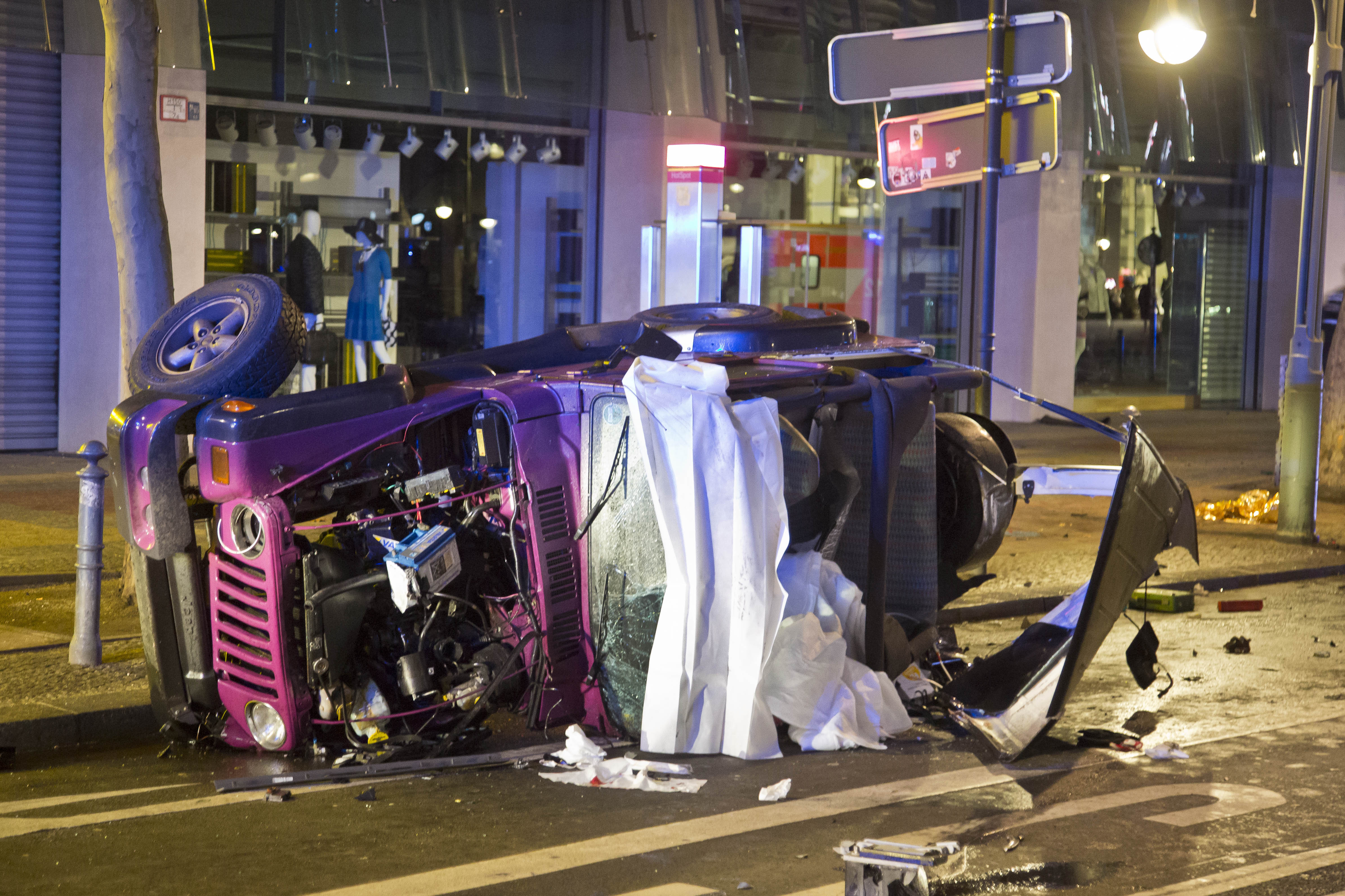 Der verunglückte rosa Jeep liegt auf der Seite, dahinter hängt ein Banner mit einem Fotos des Kudamms.