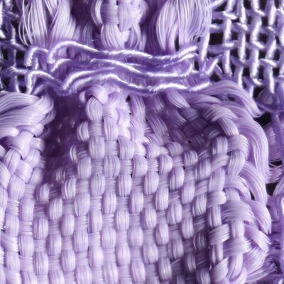 Detailaufnahme eines lilafarbenen Gewebes. Durch zwei unterschiedlich elastische Garne, Gummilitze und Seide, tritt das Blasenmuster des Stoffes besonders hervor. 