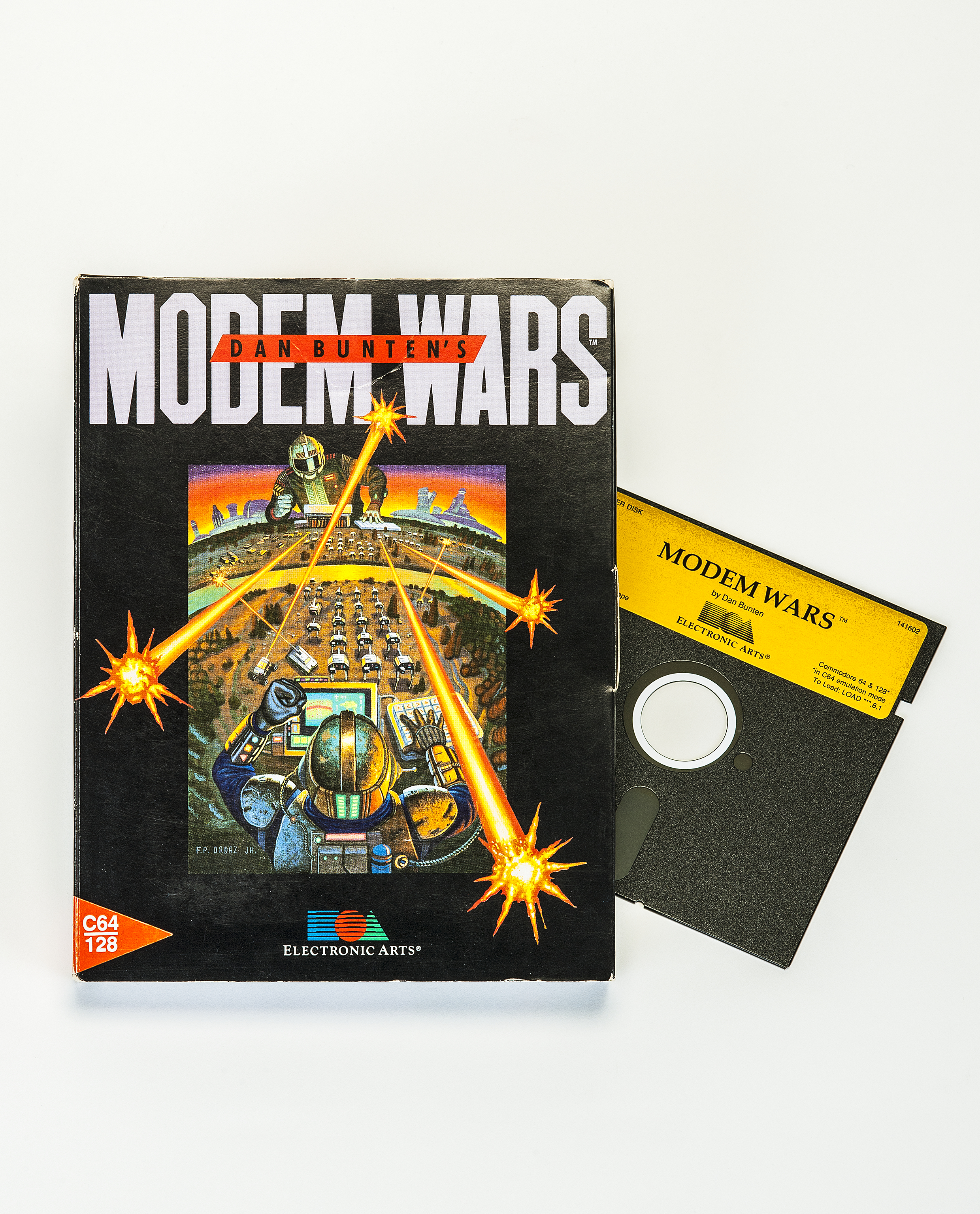 Die Hülle des Computerspiels Modem Wars. Rechts aus der Hülle herausgezogen ist die 5-1/4-Zoll Floppy Disk, auf der das Spiel gespeichert ist. Das Bild auf dem Cover zeigt zwei Spieler in futuristischen Rüstungen, die über einen Screen und Tastaturen Panzerarmeen befehligen.