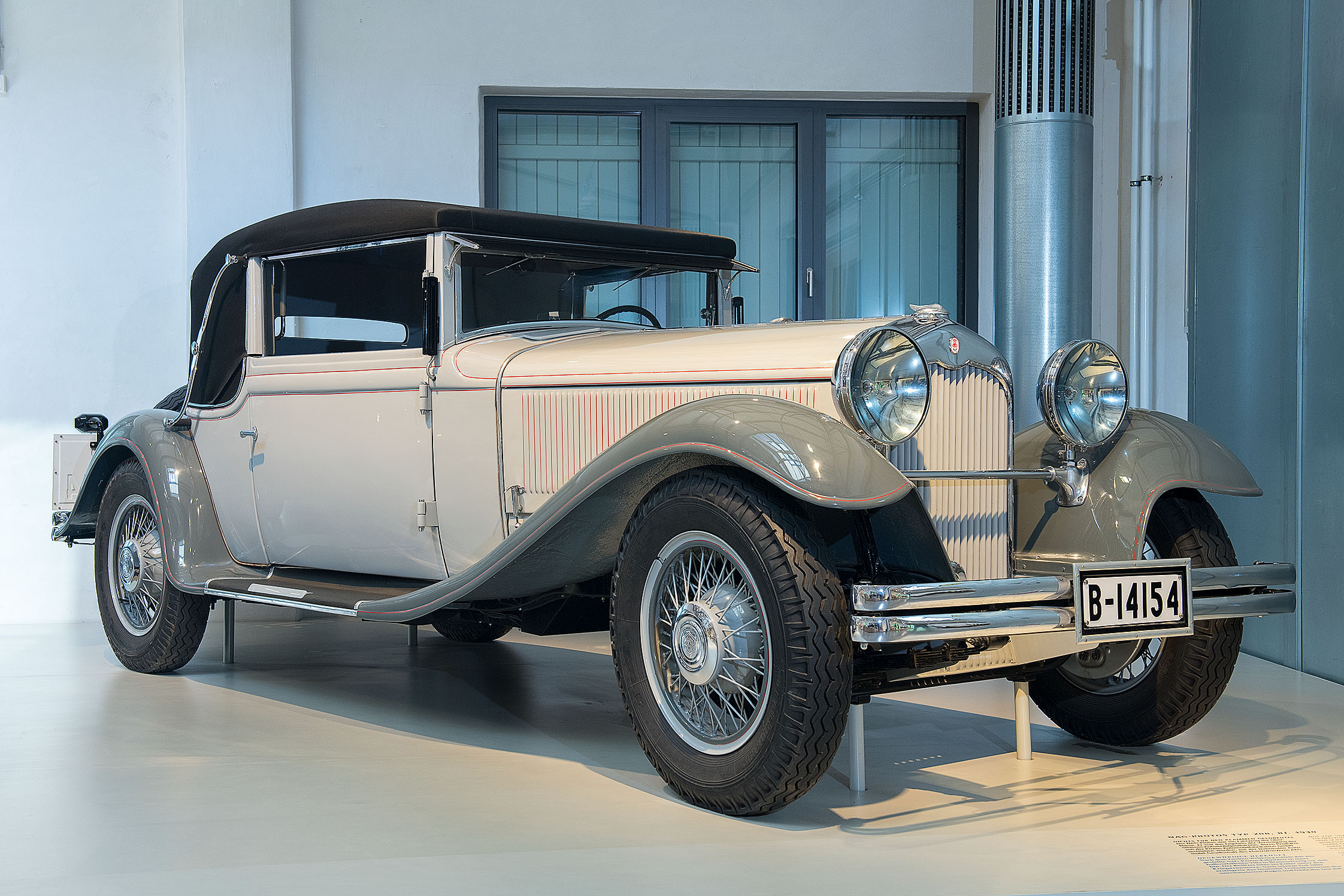 Die Karosserie des NAG Protos 208 ist weiß lackiert, die weit geschwungenen Kotflügel sind grau lackiert. Das Auto hat eine sehr lange Kühlerhaube und zwei große, runde Scheinwerfer vor dem Kühlergrill. Das Verdeck ist schwarz und lässt sich zurückschieben.