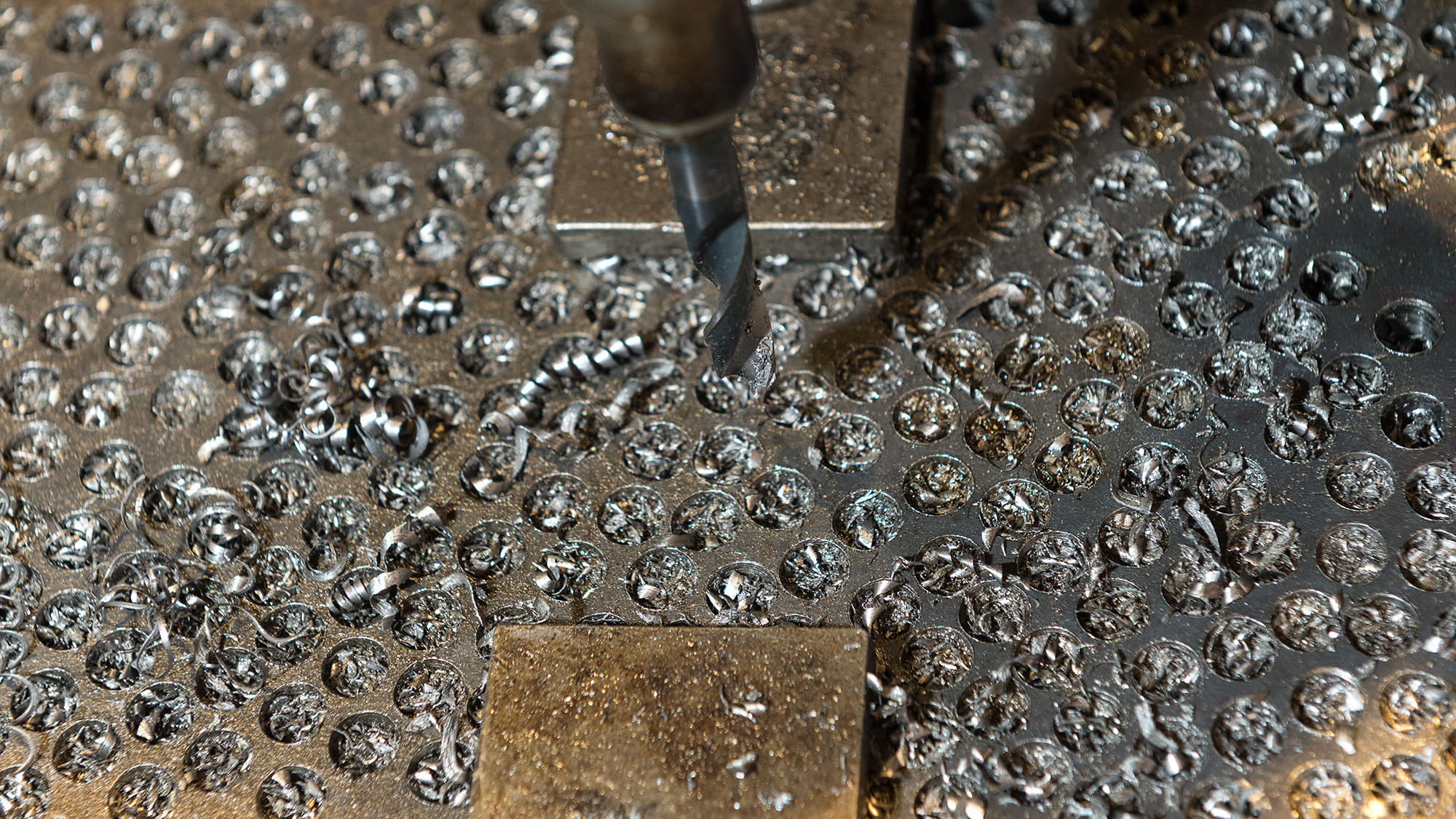 Ein Metallstück, in das kreisrunde Löcher eingefräst sind