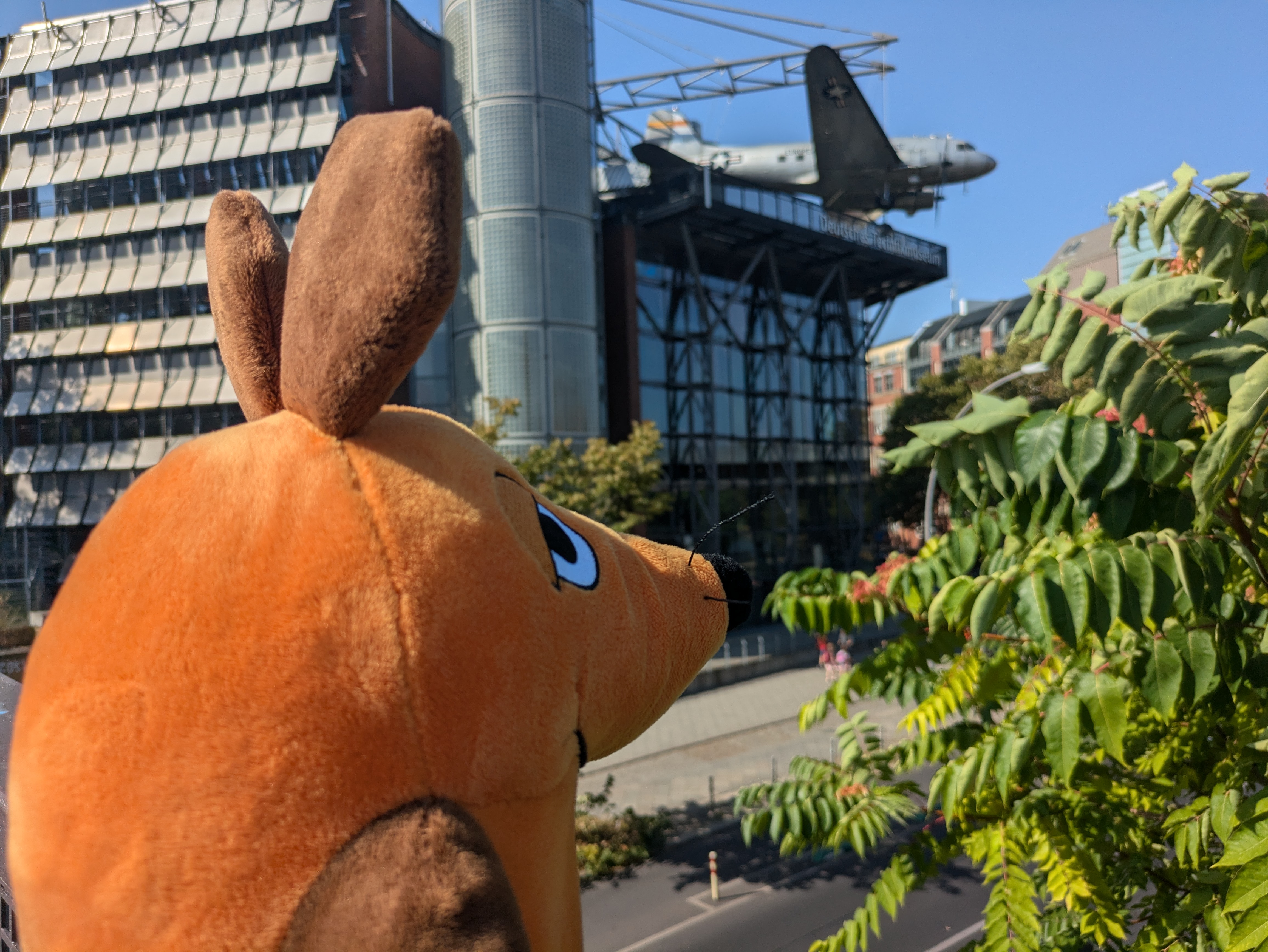 Die Maus blickt aus der Entfernung auf das Deutsche Technikmuseum mit dem Rosinenbomber im Hintergrund 