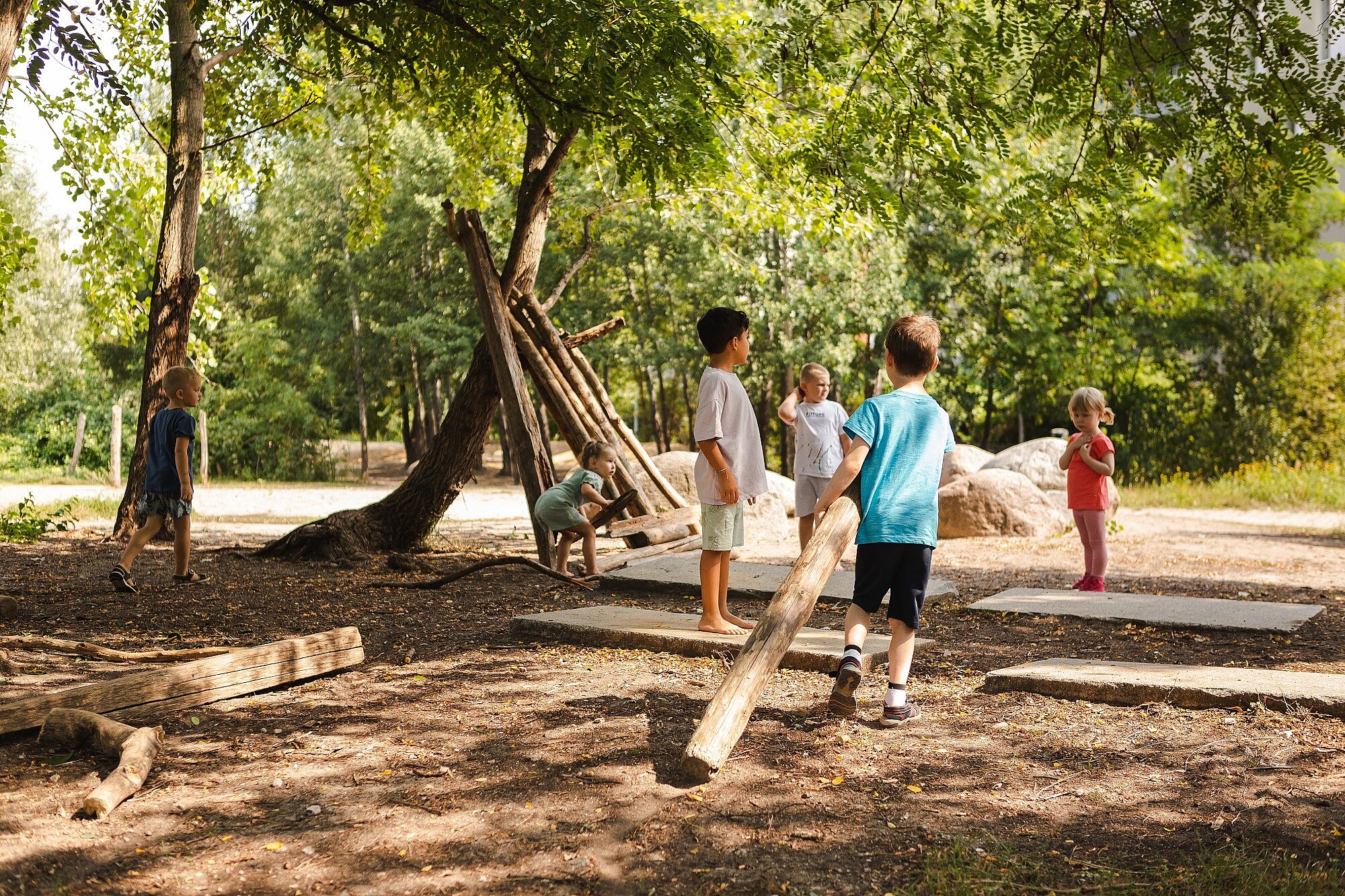 Eine Gruppe Kinder baut in einem Wald etwas aus Holz.