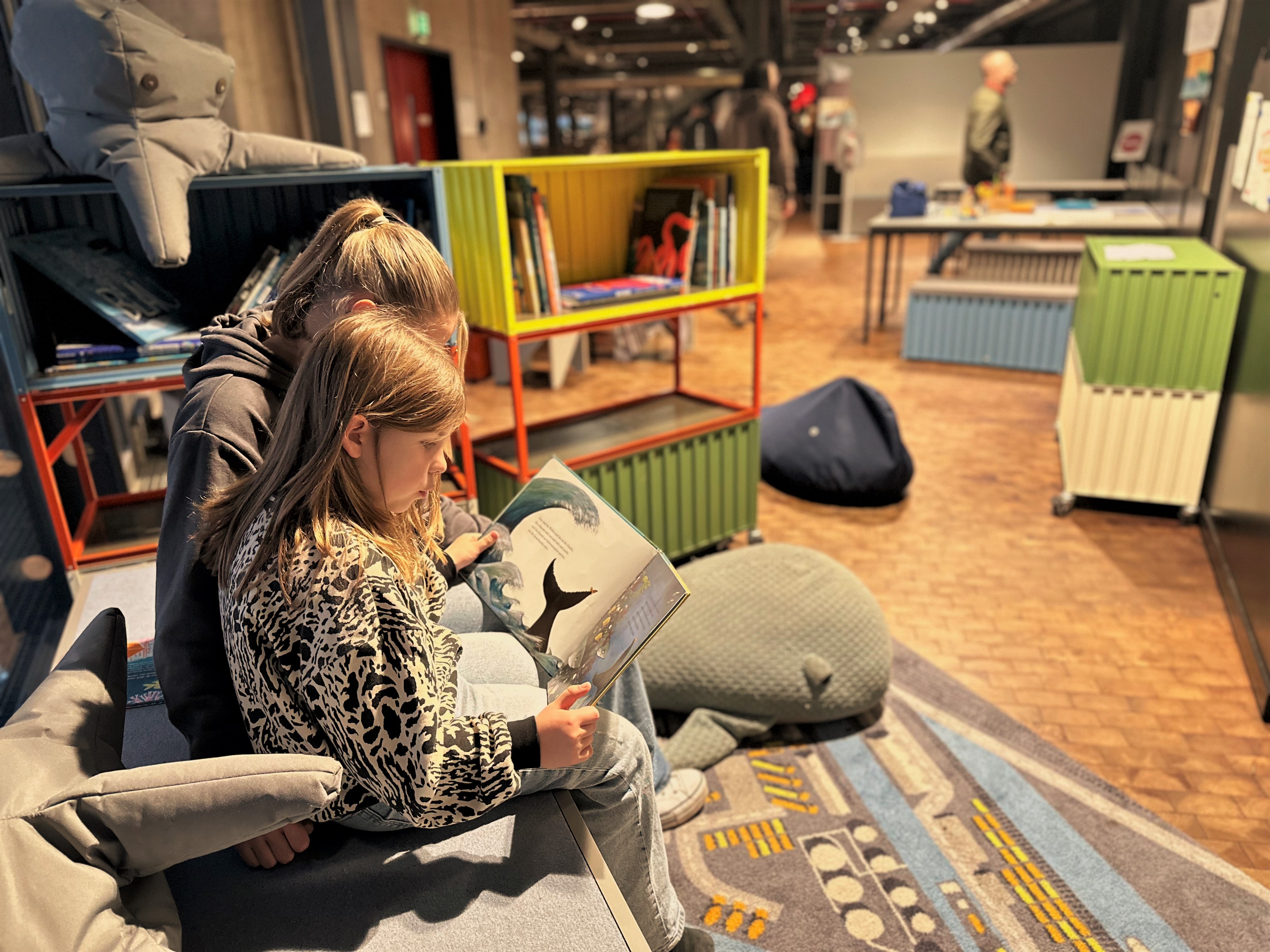 Zwei Kinder schauen sich auf der Mitmachinsel in der Schifffahrtsausstellung im Deutschen Technikmuseum ein Buch an.