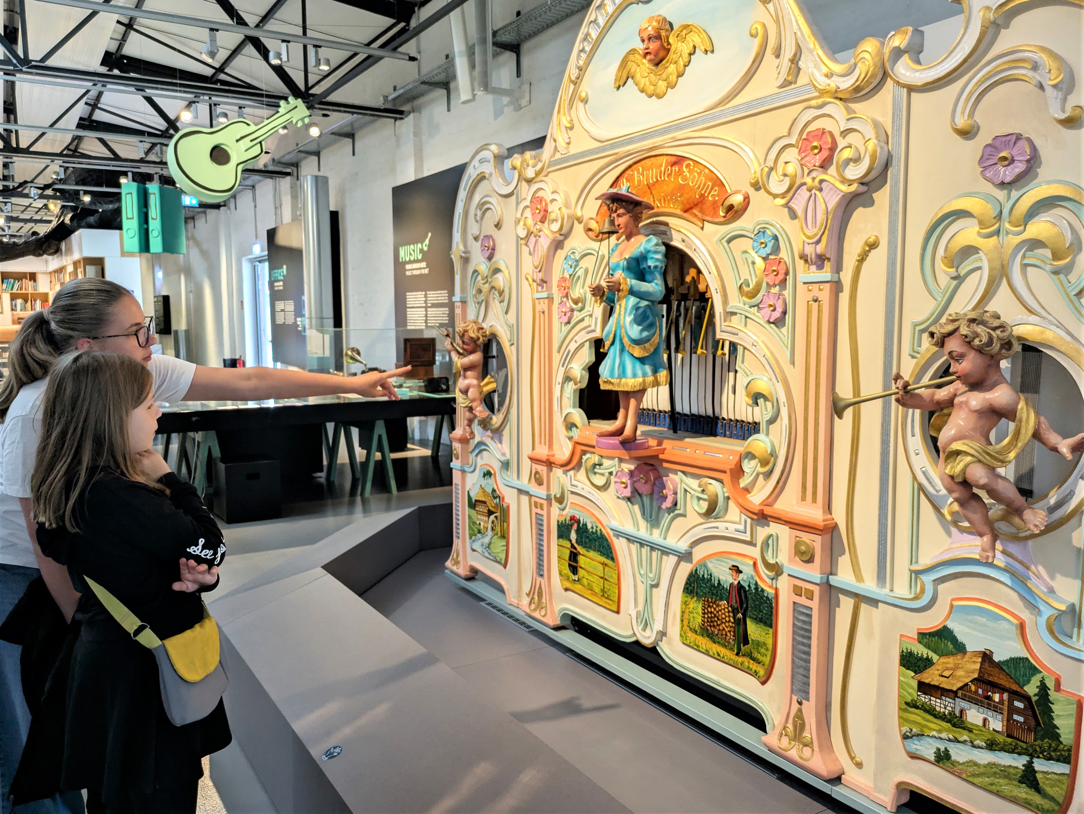 Zwei Mädchen stehen in der Dauerausstellung "Das Netz" vor einer bunten, historischen Orgel.