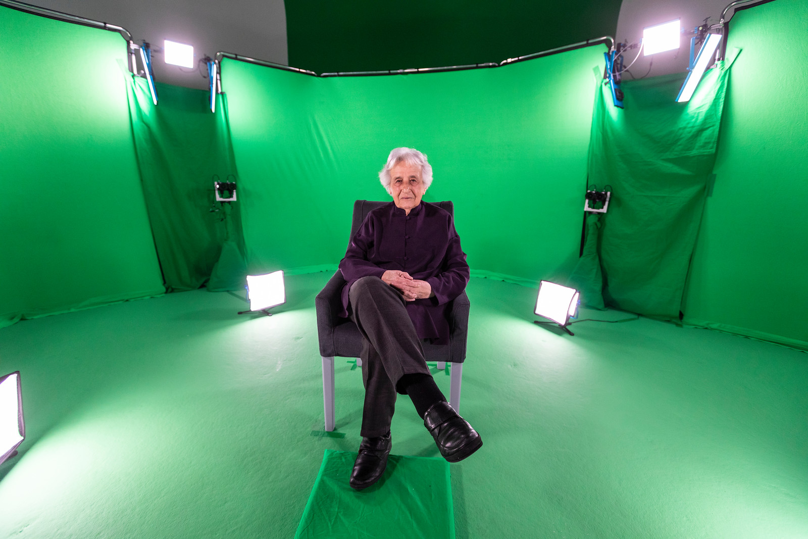 Eine schwarz gekleidete ältere Frau vor einem Green Screen