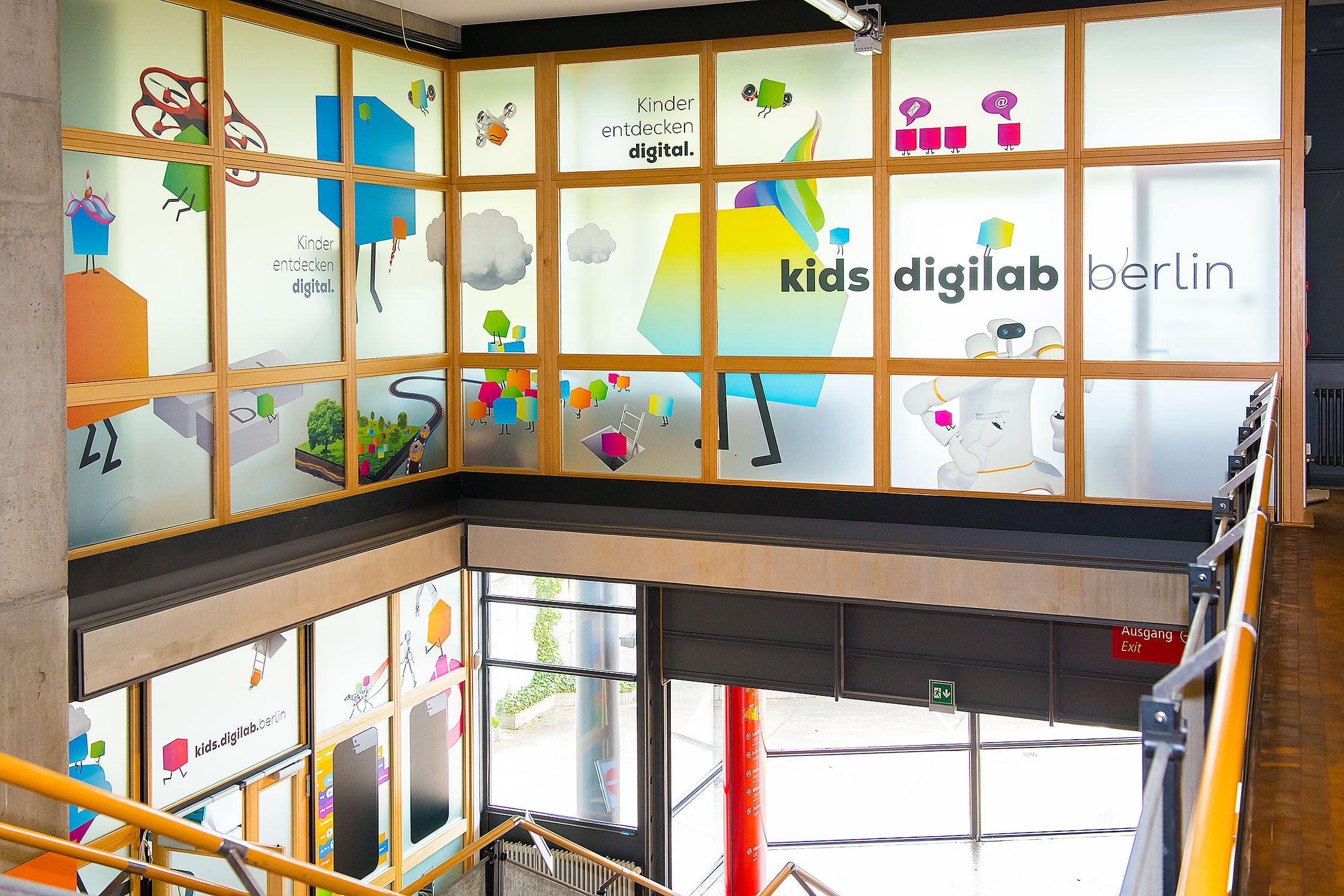 Ansicht von der Innentreppe auf Glasfassade der oberen Etage des kids.digilab und unteren Eingang des kids.digilab.