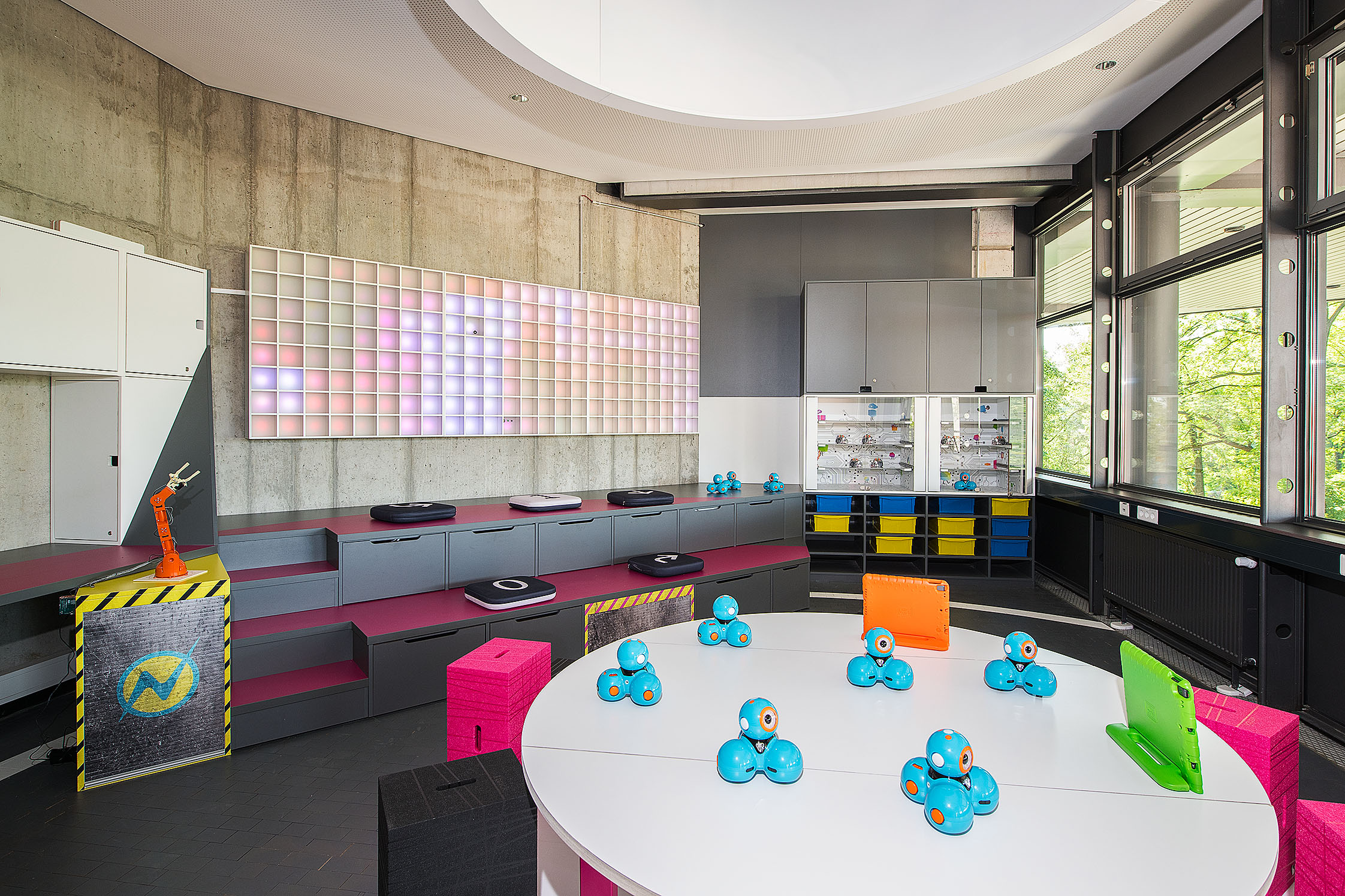 Blick in den Innenraum des kids.digilab.berlin mit bunten Möbeln, Tischen mit Robotikspielzeug und farbenfroher Wandgestaltung.