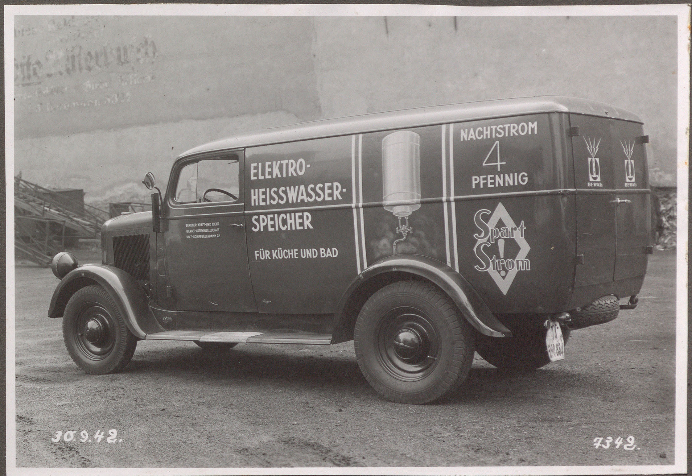 Das Bild zeigt einen kleinen Lieferwagen. Auf der Seite befinden sich die Aufschriften „Elektro-Heisswasser-Speicher für Küche und Bad“ sowie „Nachtstrom 4 Pfennig. Spart Strom!“ Es ist ein Heißwasserboiler abgebildet. 