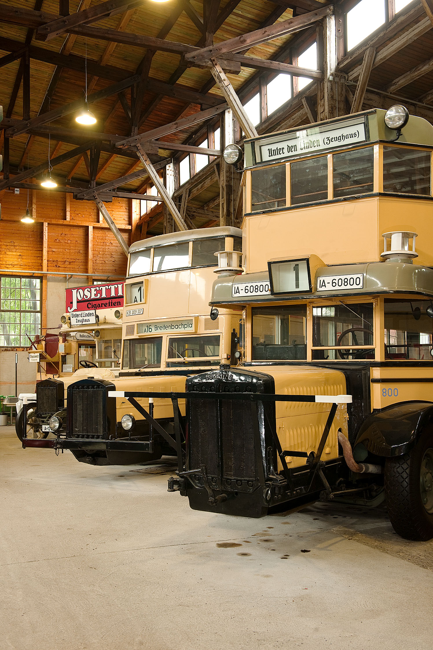Die historischen gelben Busse stehen aufgereiht im Depot für Straneverkehr des Deutschen Technikmuseums in der Monumentenhalle.