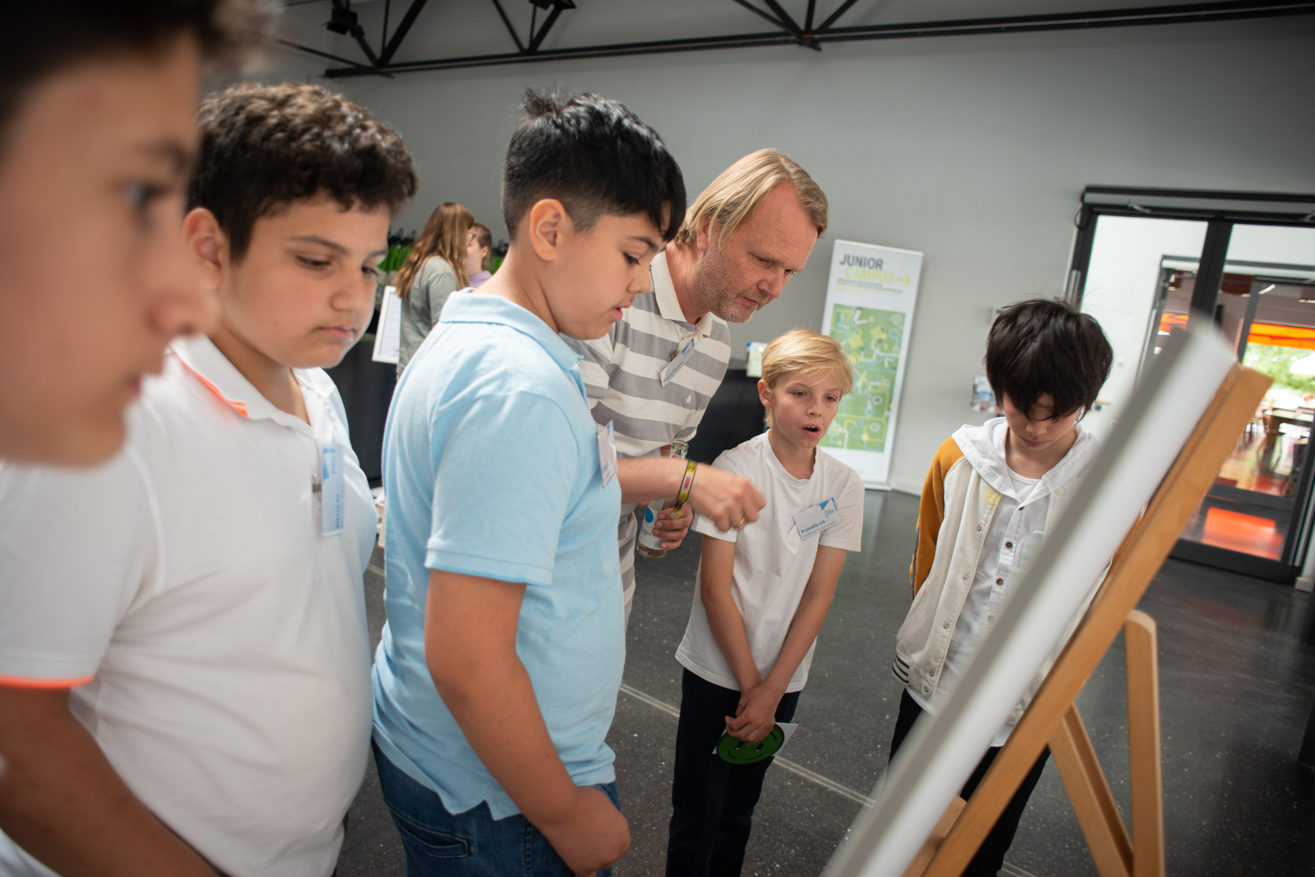 Einige Kinder stehen mit einem Erachsenen um ein Whiteboard herum.