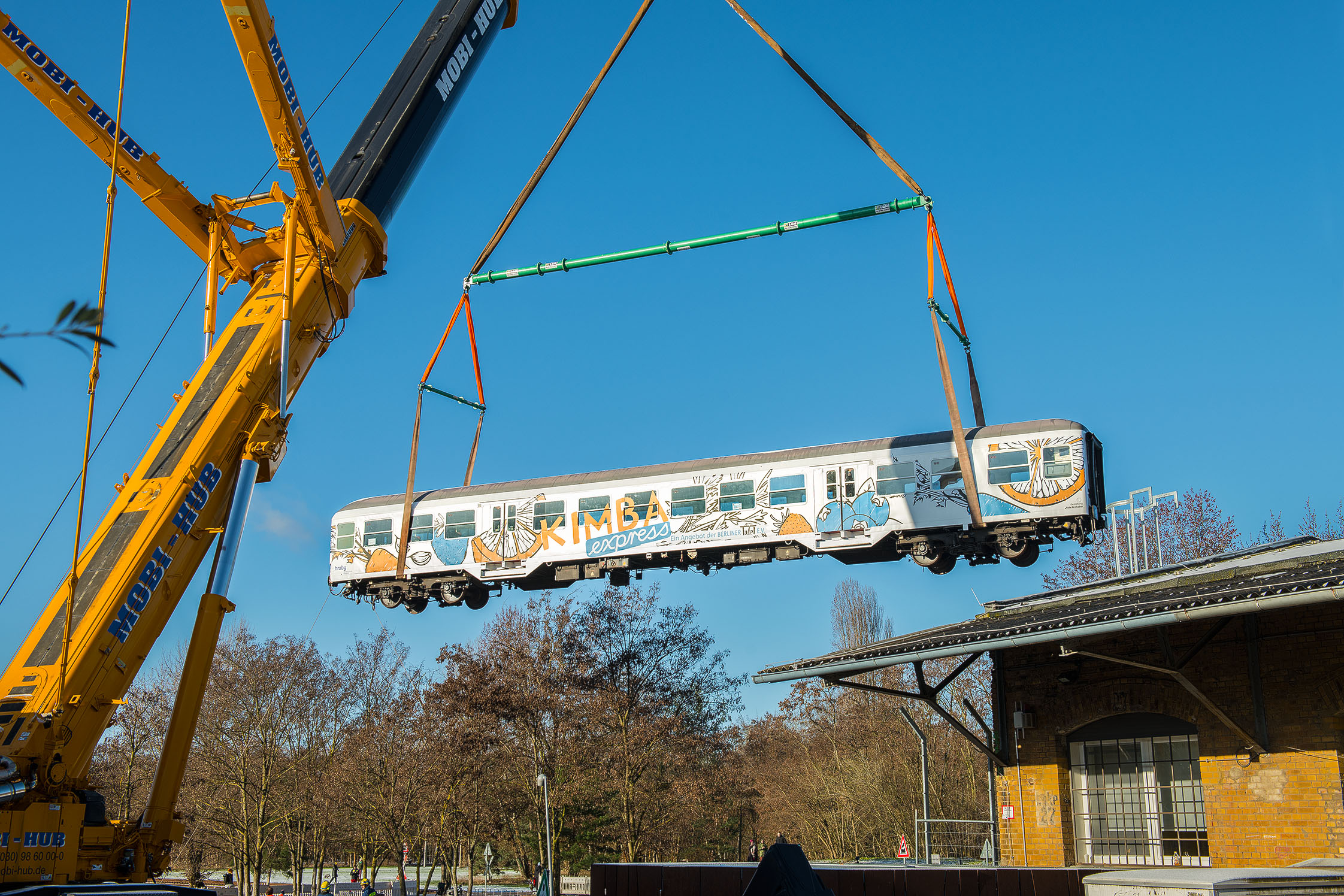 Ein Eisenbahnwagen hängt an einem Kran und schwebt in der Luft