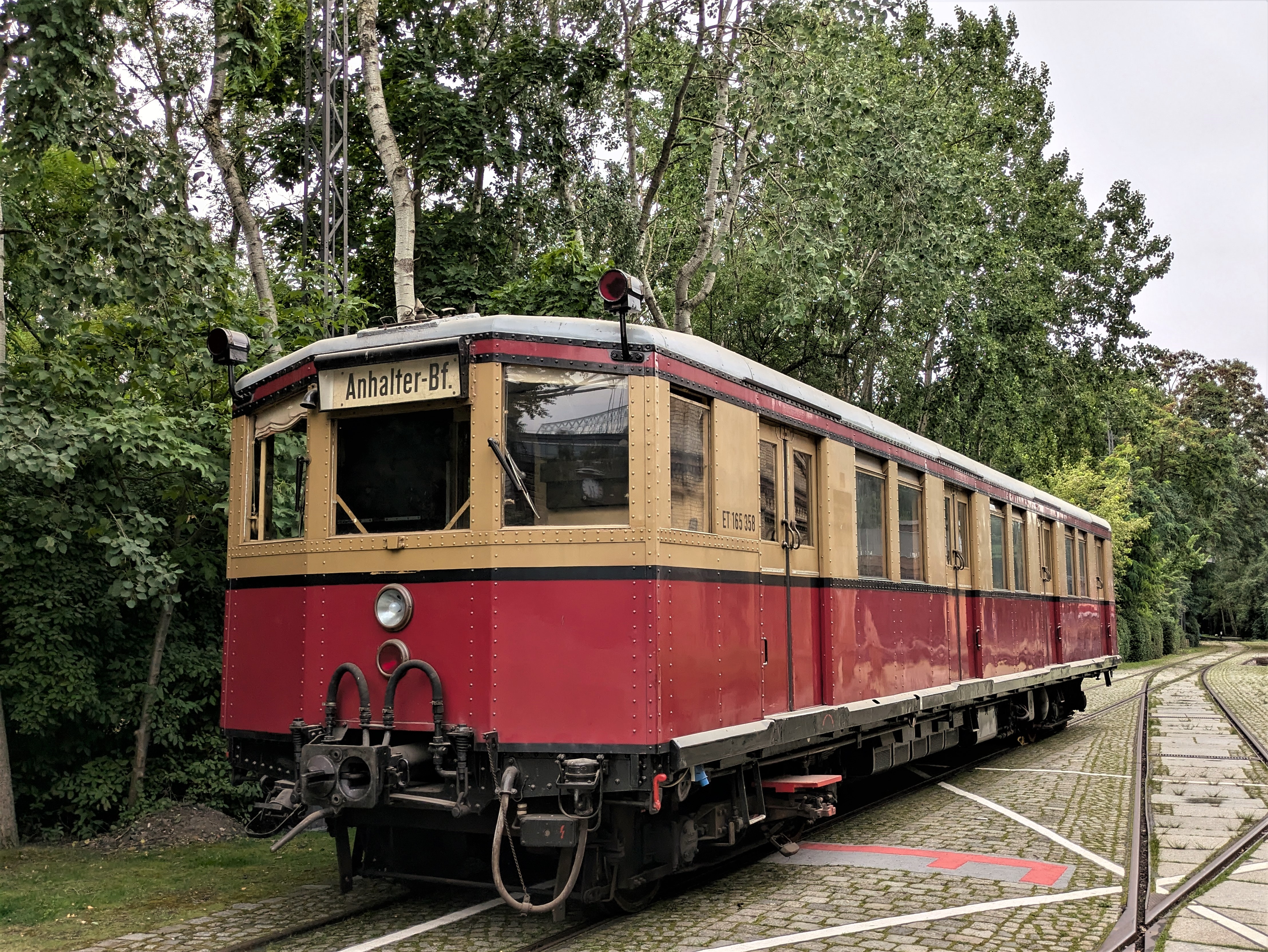 Foto einer gelb-roten S-Bahn auf Schienen in einem Park.