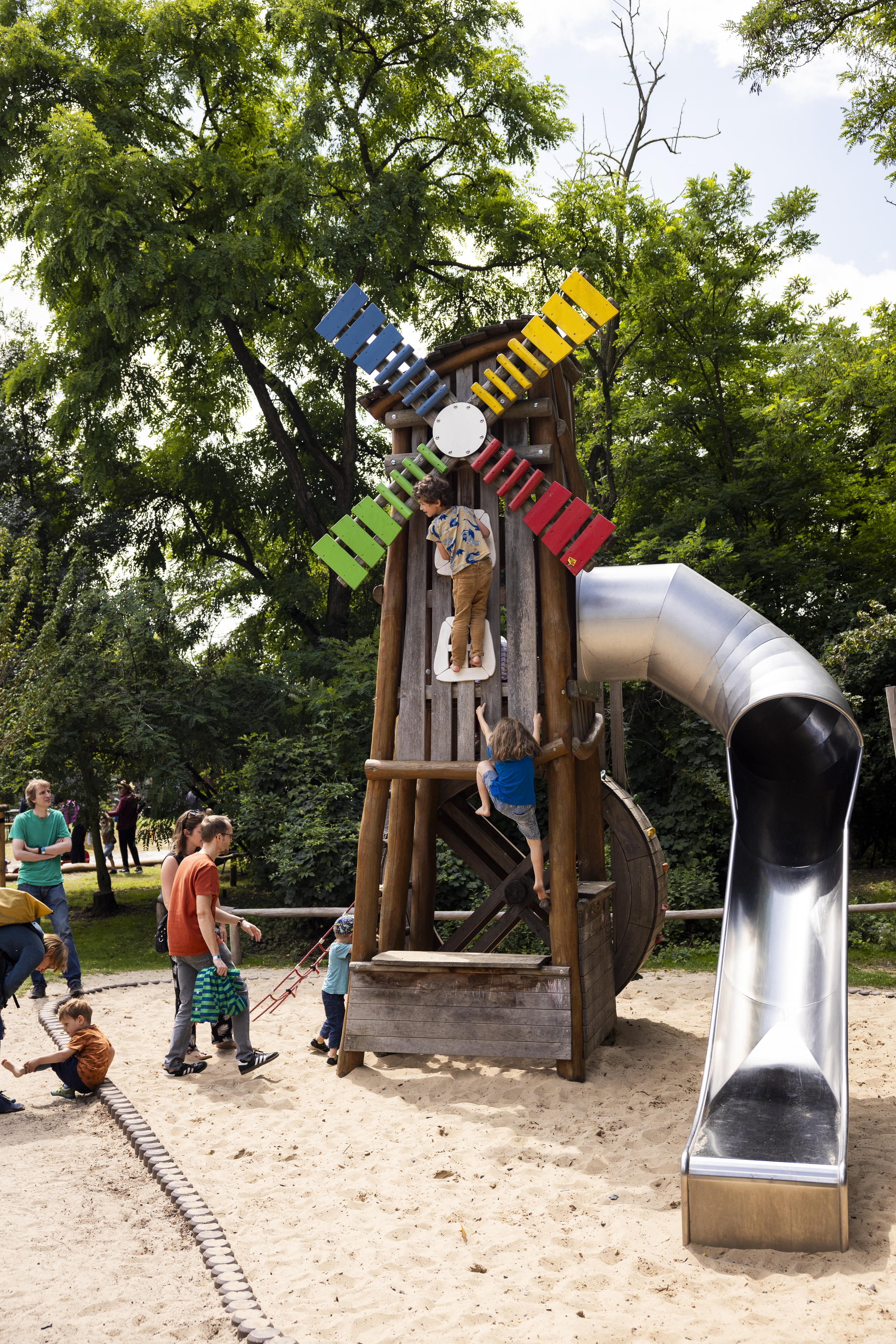 Kinder spielen an einer Mini-Mühle in einem Sandkasten in einem Park.