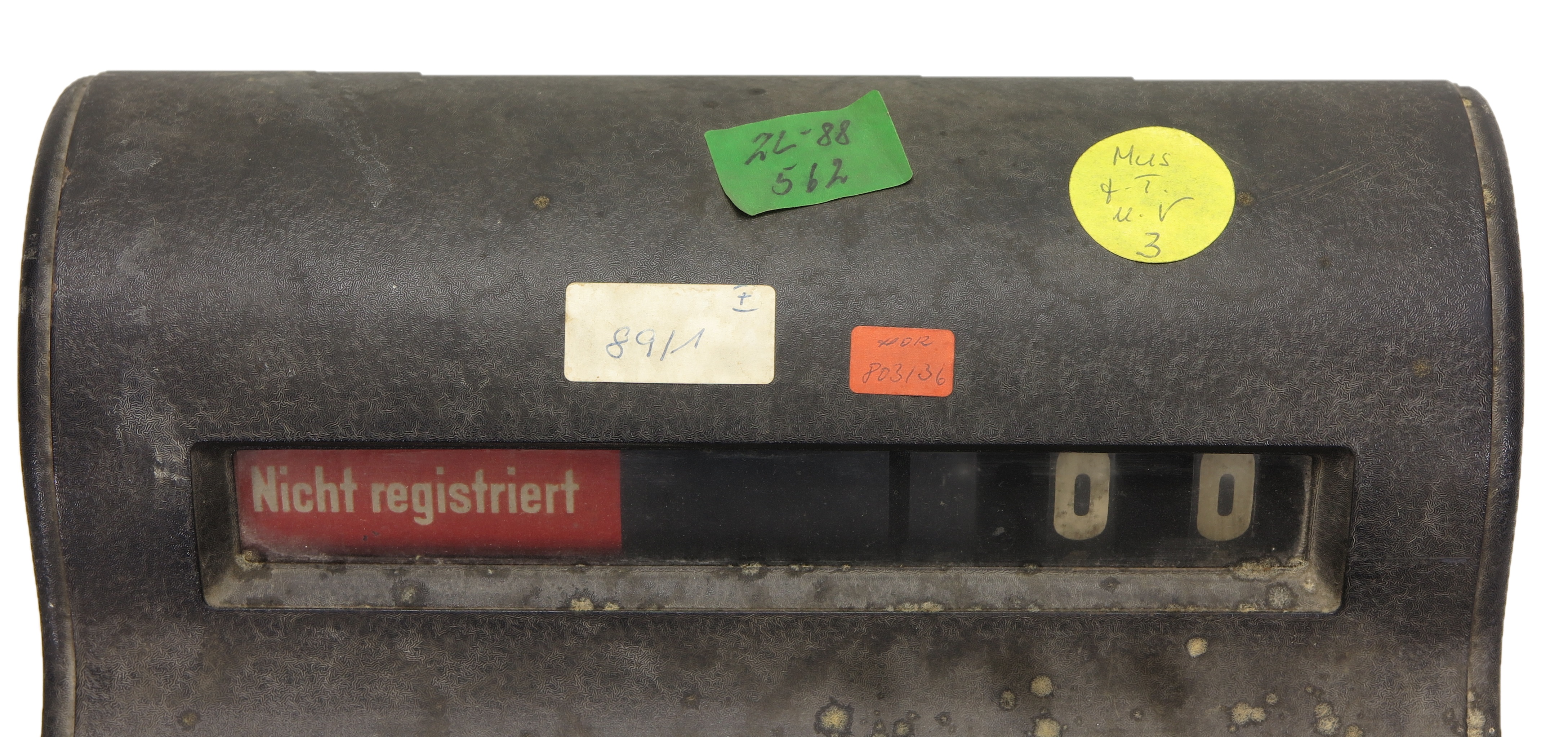Oberer Teil einer Registrierkasse aus den 1930er Jahren mit vier farbigen Aufklebern der KuA. Die Aufkleber tragen Zahlen und Buchstaben.